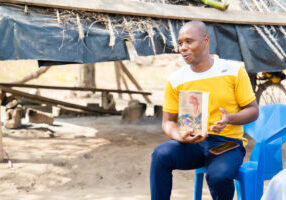 Pastor Kouadio Kouassi Guillaume (short sleeved yellow shirt) pictured with members of his congregation discussing the Africa Bible Commentary. Kouadio serves as Pastor of Christian Missionary Alliance Evangelical church in Sahabo, Yamoussoukro, studies as a seminary student at FATEAC, third year Masters, going on to do PhD. 

* Oversees/pastors 8 different churches in the Sahabo parrish. 
* CMA planted the eight churches as communities of believers sprang up following evangelism events. 
* These churches were planted in 1983. 
* Kouadio began serving in 2014 following his undergrad BA in theology at Alliance Bible Institute of Yamoussoukro. 
* He is the only person with Bible College training and immediately began serving all eight churches as the one with the highest level of training.